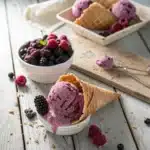 Black Raspberry Ice Cream: A Bold and Creamy Favorite You’ll Love 7 Scoops of black raspberry ice cream in a waffle cone with mixed berries on a rustic wooden table